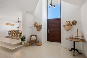 Ein modernes Interieur mit Essbereich, Korbmöbeln, einer Holztür und an der Wand befestigten Hüten.