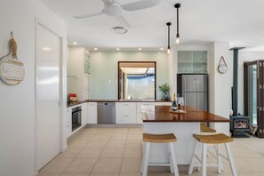 Eine moderne Küche mit Kochinsel, weißen Schränken, Edelstahlgeräten und Deckenventilator.