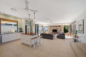 Eine moderne Küche mit Kochinsel, ein Essbereich mit einer Couch und ein Fernseher im Wohnzimmer.