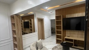 Una sala de estar moderna con un sofá modular, estanterías integradas, un televisor de pantalla plana y piso de mármol.