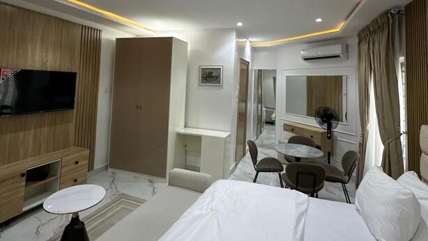 Habitación de hotel con cama, televisión, escritorio, silla, espejo y aire acondicionado.