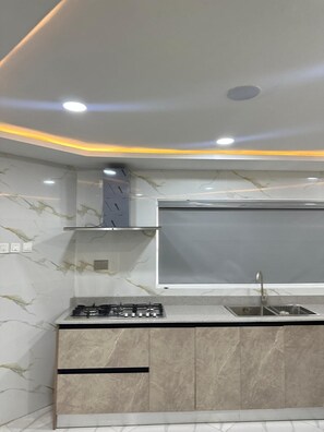 A modern kitchen with a gas stove, a sink, and a marble backsplash. - Glover Apartments (Lagos)