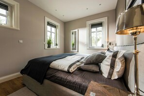 Ein Schlafzimmer mit einem Bett, Nachttischlampen und Fenstern mit Vorhängen.