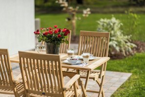 Ein Holztisch mit Stühlen, eine Vase mit roten Blumen und ein Glas Milch.