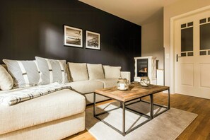 Ein Wohnzimmer mit Sofa, Couchtisch und Kamin.