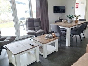 Een moderne eetruimte met een tafel, stoelen en een televisie.