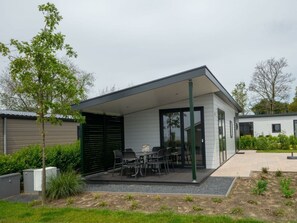 Een modern huis met een overdekte patio, tuinmeubilair en een tuin.