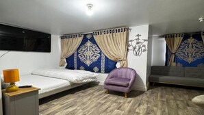 A bedroom with a bed, a chair, a sofa, a TV, and a wall with a decorative pattern. - Standard Double Room (Bolton)
