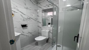 A bathroom with a toilet, sink, and glass-enclosed shower. - Standard Double Room (Bolton)
