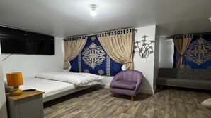 A room with a bed, a chair, a sofa, a lamp, and a wall with a decorative design. - Standard Double Room (Bolton)