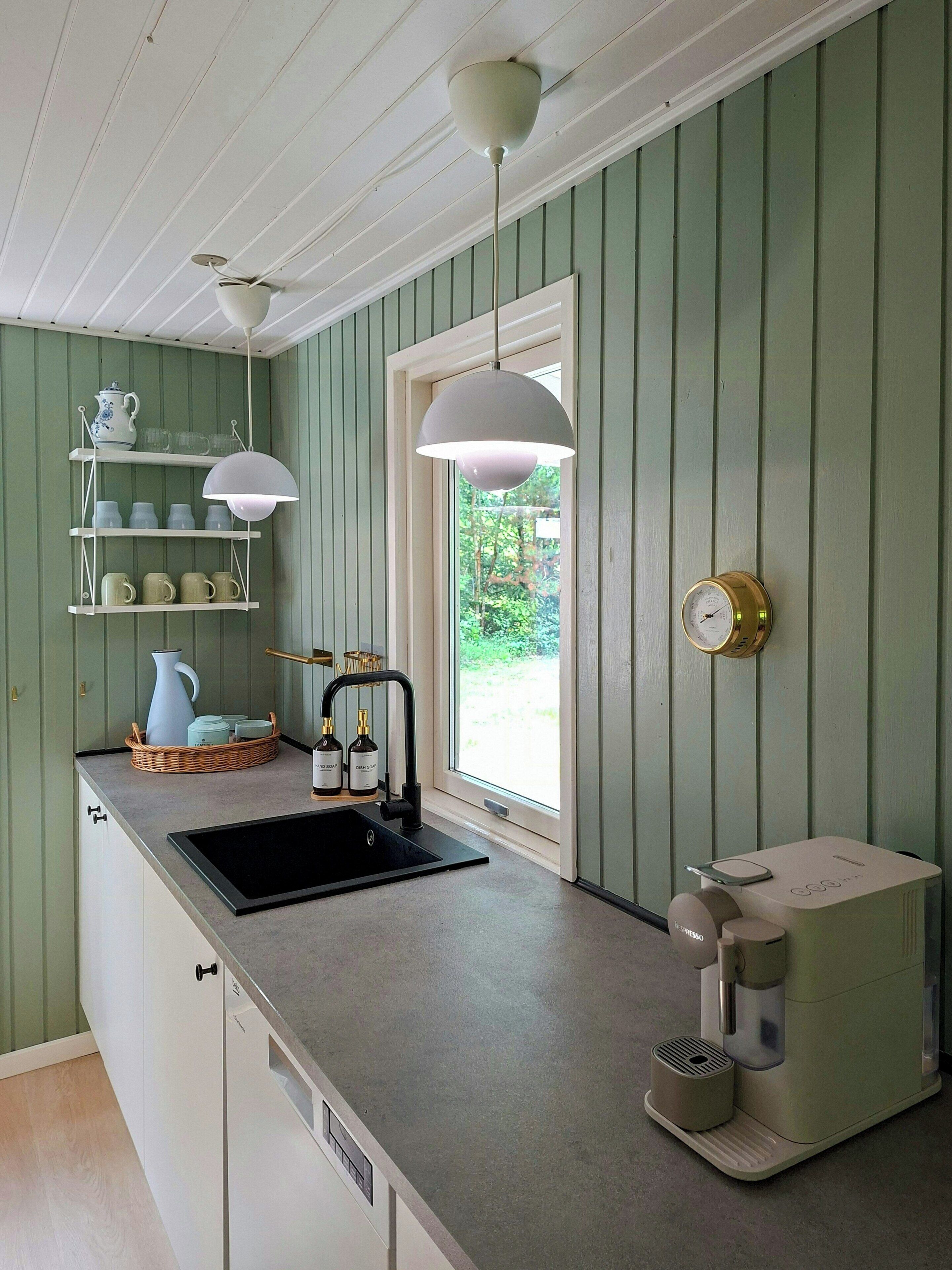 Een keuken met een spoelbak, een koffieapparaat en een raam met uitzicht op groen.
