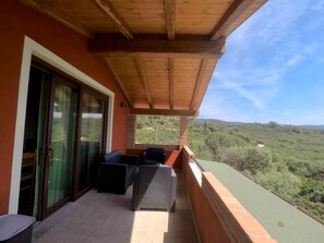 Ein Balkon mit Holzboden, einer Schiebeglastür und Gartenmöbeln.