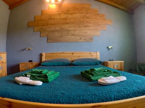 Ein Schlafzimmer mit einem Holzkopfende, einem Bett mit türkisfarbener Bettwäsche und einer Holztreppe.