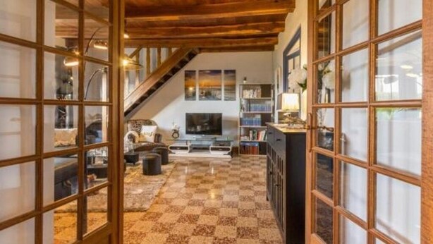Uma sala de estar ampla com piso xadrez, televisão e escada para um andar superior.