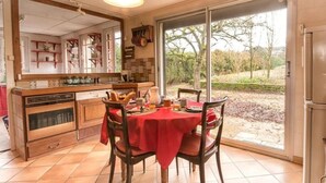 Uma cozinha com mesa de jantar, cadeiras, uma janela grande e vista para o exterior.