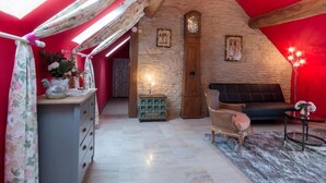Um quarto de sótão aconchegante com teto inclinado, porta de madeira, relógio e sofá.