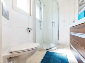 A modern bathroom with a toilet, a glass shower enclosure, and a wooden vanity. - Holiday Home in Noordwijk With Terrace (Noordwijk)