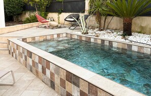 A rectangular pool with tiled edges, surrounded by a patio area with seating and plants. - Awesome apartment in Marseille (Marseille)