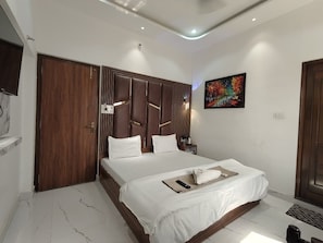 Une chambre d’hôtel moderne avec un grand lit, une tête de lit en bois, un tableau au mur et une porte dotée d’une poignée.