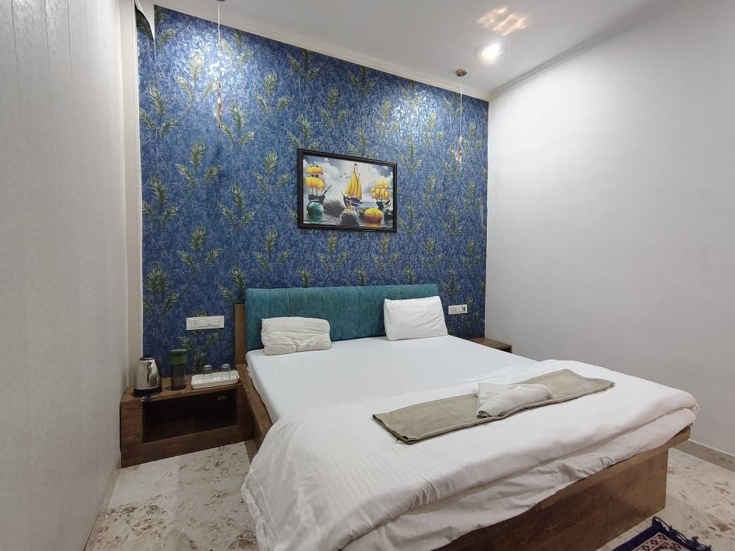 A bedroom with a bed, a nightstand, a framed picture, and a blue patterned wall.