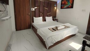 A hotel room with a bed, a wardrobe, a painting, and a marble floor.