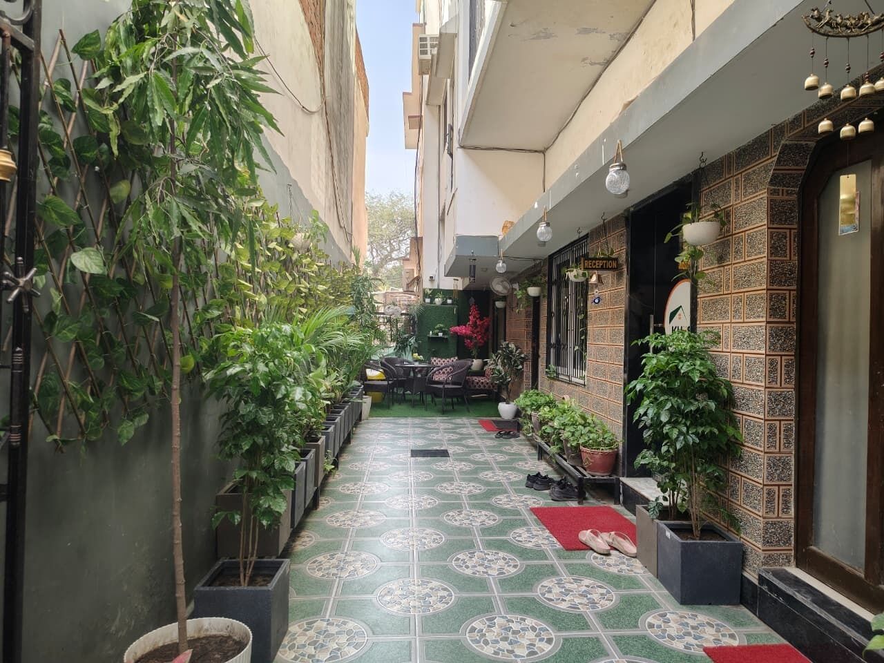 Un estrecho callejón con macetas, una zona de recepción y un suelo de baldosas.