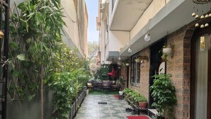 A narrow alleyway with potted plants, a reception area, and a tiled floor.