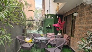 A small outdoor patio with wicker furniture, a round table, and potted plants.