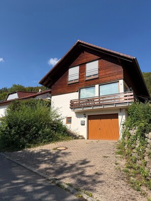 A two-story house with a wooden facade, a balcony, and a garage.