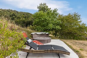 A sunlit outdoor seating area with wicker furniture and a concrete pathway.