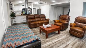 A modern living room with a sofa set, a recliner, a coffee table, and a patterned rug.