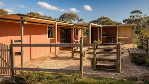 A rustic building with a wooden exterior, a fenced outdoor area, and a small structure with a bench.
