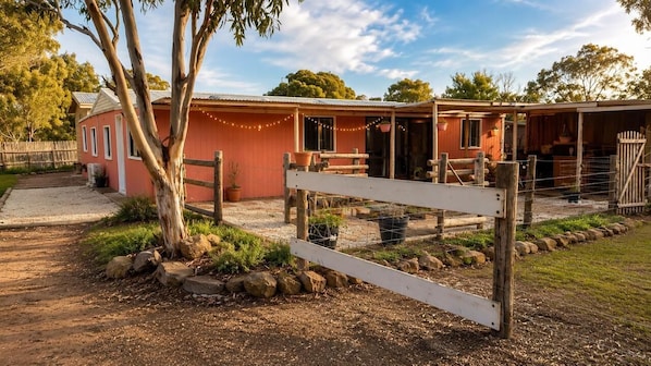 A red building with a fenced area, a tree, and a gravel path.