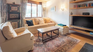 A living room with a sofa, armchair, coffee table, and a flat-screen TV.