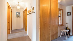 A hallway with wooden doors, a painting on the wall, and a small stool with a pot.