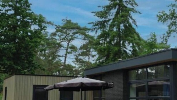 Een modern gebouw met een patio, buitenmeubels en een groot raam.