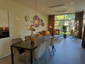 Een moderne keuken met een eethoek, een klok aan de muur en een groot raam met gordijnen.