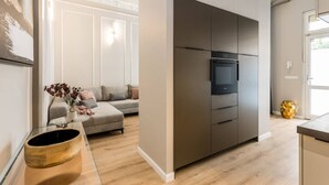 Una cocina moderna con horno y microondas integrados, un sofá gris y una mesa de centro de madera.