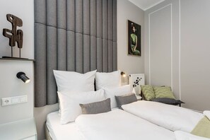 Ein modernes Schlafzimmer mit einem großen Bett, einem Kopfteil mit vertikalen Lamellen, einem Nachttisch mit Lampe und einem Wandbild.