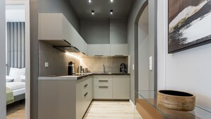 Una cocina moderna con una isla central, una cafetera y un cuenco de madera sobre una mesa de vidrio.