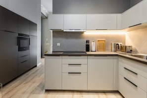 Eine moderne Küche mit Einbauofen, Mikrowelle, Edelstahltoaster und Schneidebrett.