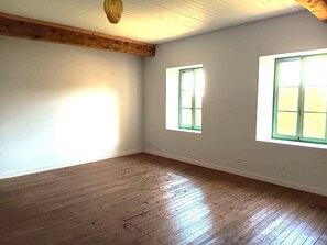 A room with wooden flooring, white walls, and two windows with green frames. - Spacious mountain home for families and groups in the Haut Jura! (Les Bouchoux)