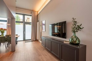Ein modernes Wohnzimmer mit Flachbildfernseher, einer Konsolentisch und einer Topfpflanze.