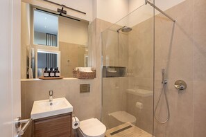 A modern bathroom with a glass-enclosed shower, a sink with a mirror, and a toilet. - Exclusive Cube loft near the main train station (Berlin)