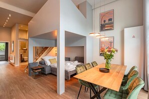 A modern interior with a dining area, a sofa, a bed, and a staircase. - Exclusive Cube loft near the main train station (Berlin)