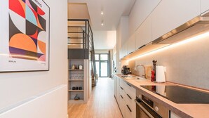 Une cuisine moderne dotée d’une cuisinière intégrée, d’une machine à café et d’un plan de travail en bois.