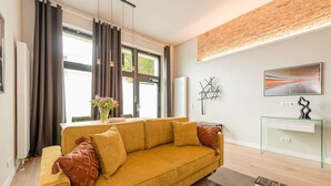 Un salon moderne avec un canapé, une console en verre et un tableau accroché au mur.