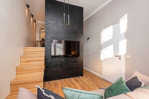 Ein modernes Interieur mit Kamin, einer Holztreppe und einer Couch mit Kissen.