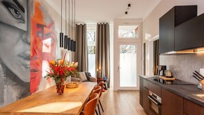 Una cocina moderna con armarios oscuros, una mesa de comedor de madera y un mural grande en la pared.