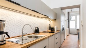 Ett modernt kök med en bänkskiva i trä, en diskho i rostfritt stål och ett stänkskydd av hexagonformade kakelplattor.